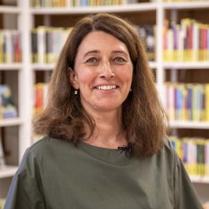 Frau in grünem Pullover vor Bücherregal
